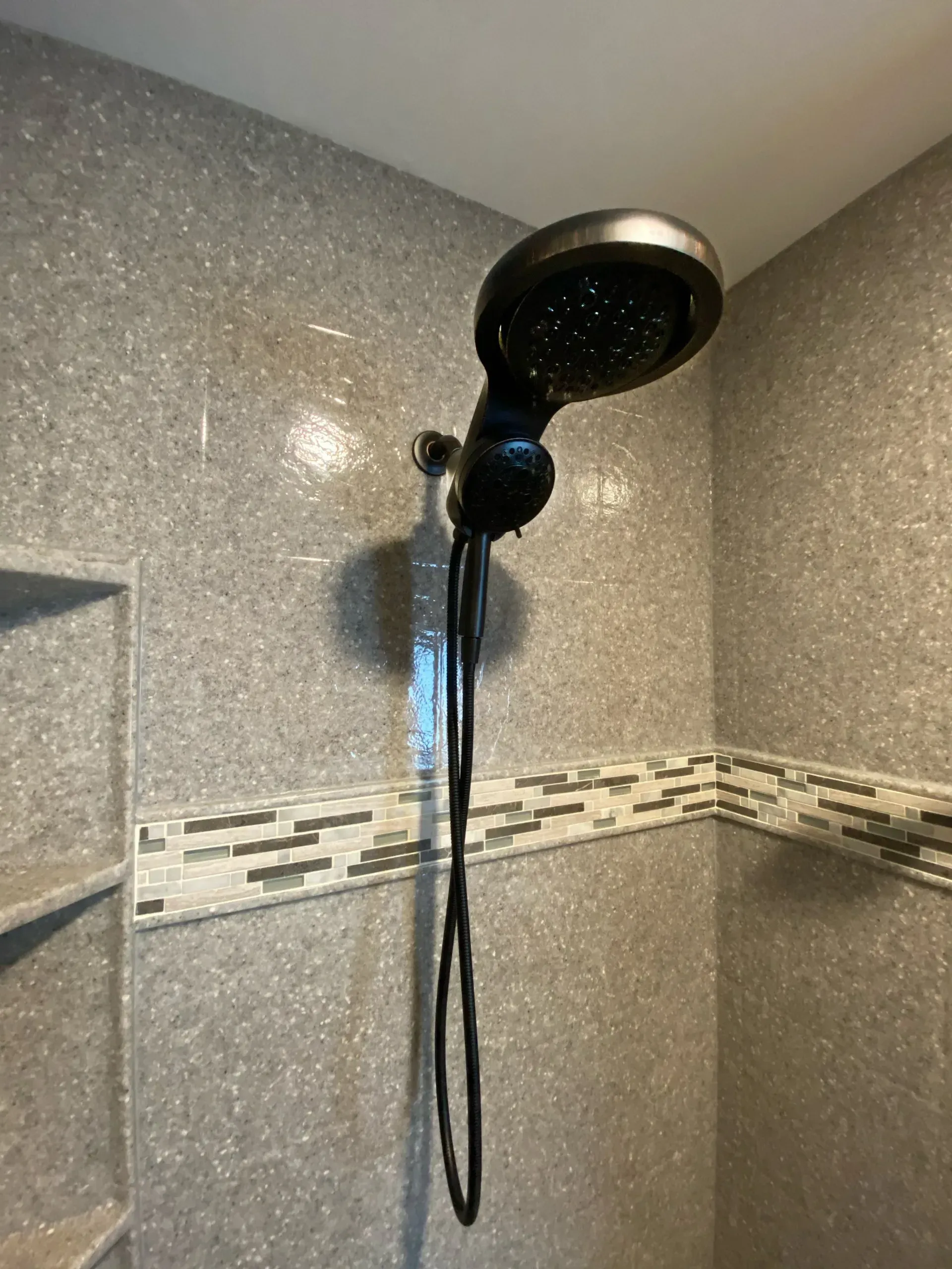 Black showerhead against gray tiled shower wall.