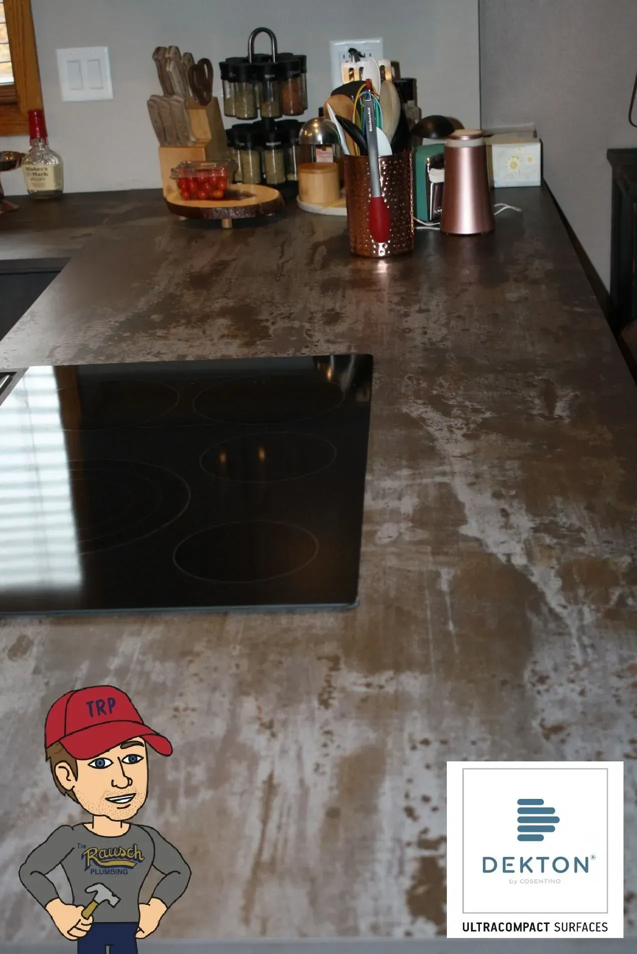 Kitchen countertop with cooktop, various kitchen tools. A cartoon man and Dekton logo are in the corner.