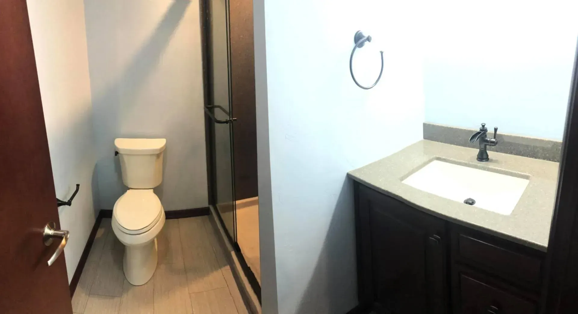 Bathroom with toilet, glass shower, and vanity with sink and dark brown cabinet.