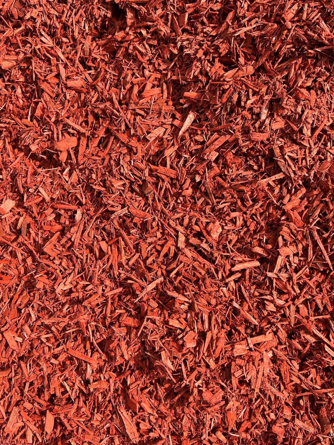 A close-up view of red-dyed wood mulch chips used for landscaping.