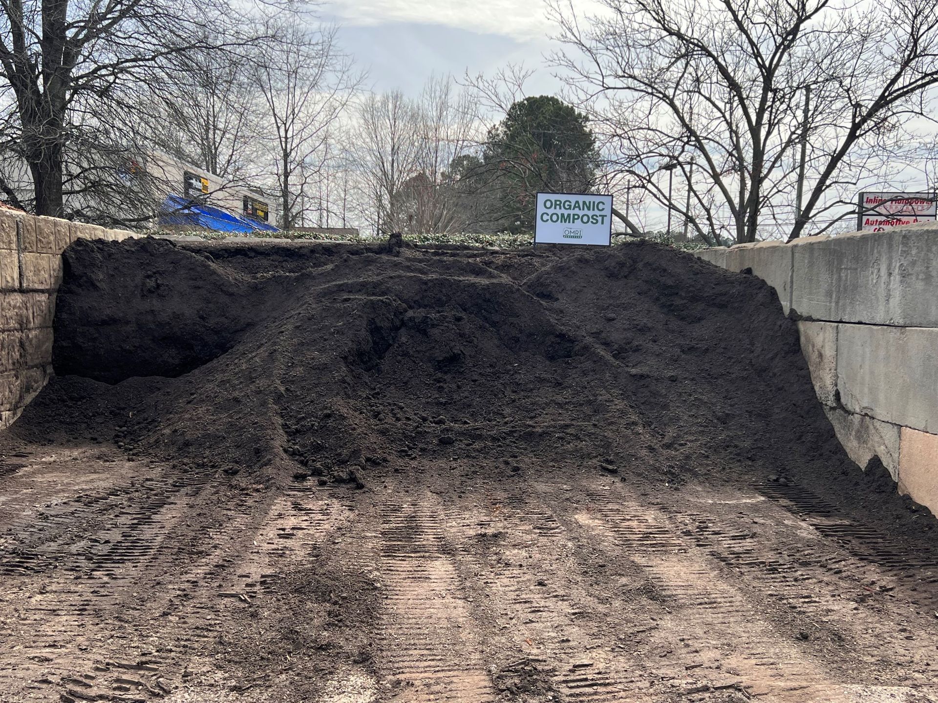 Large pile of dark compost in an outdoor bin.