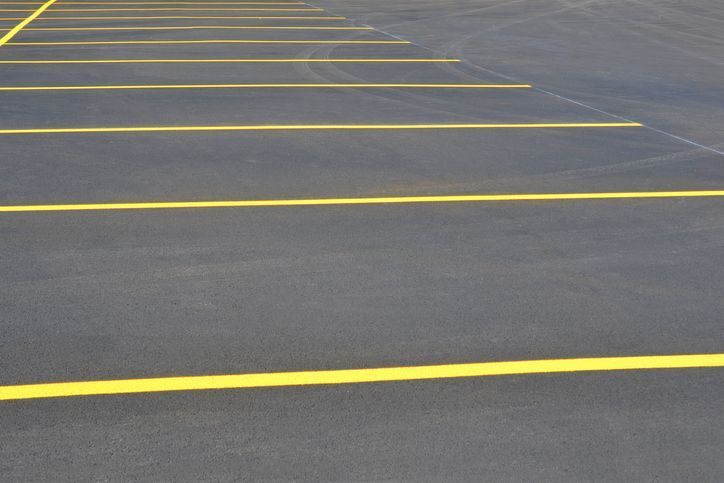 A parking lot with parallel yellow painted lines on gray asphalt.