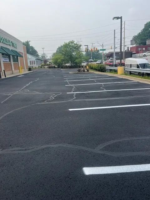 An asphalt parking lot with freshly painted white parking space lines next to a commercial building on an overcast day.
