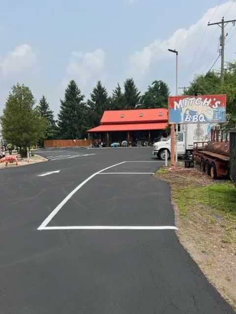 Mitch's BBQ restaurant building with a red roof, viewed from an empty parking lot on a sunny day.