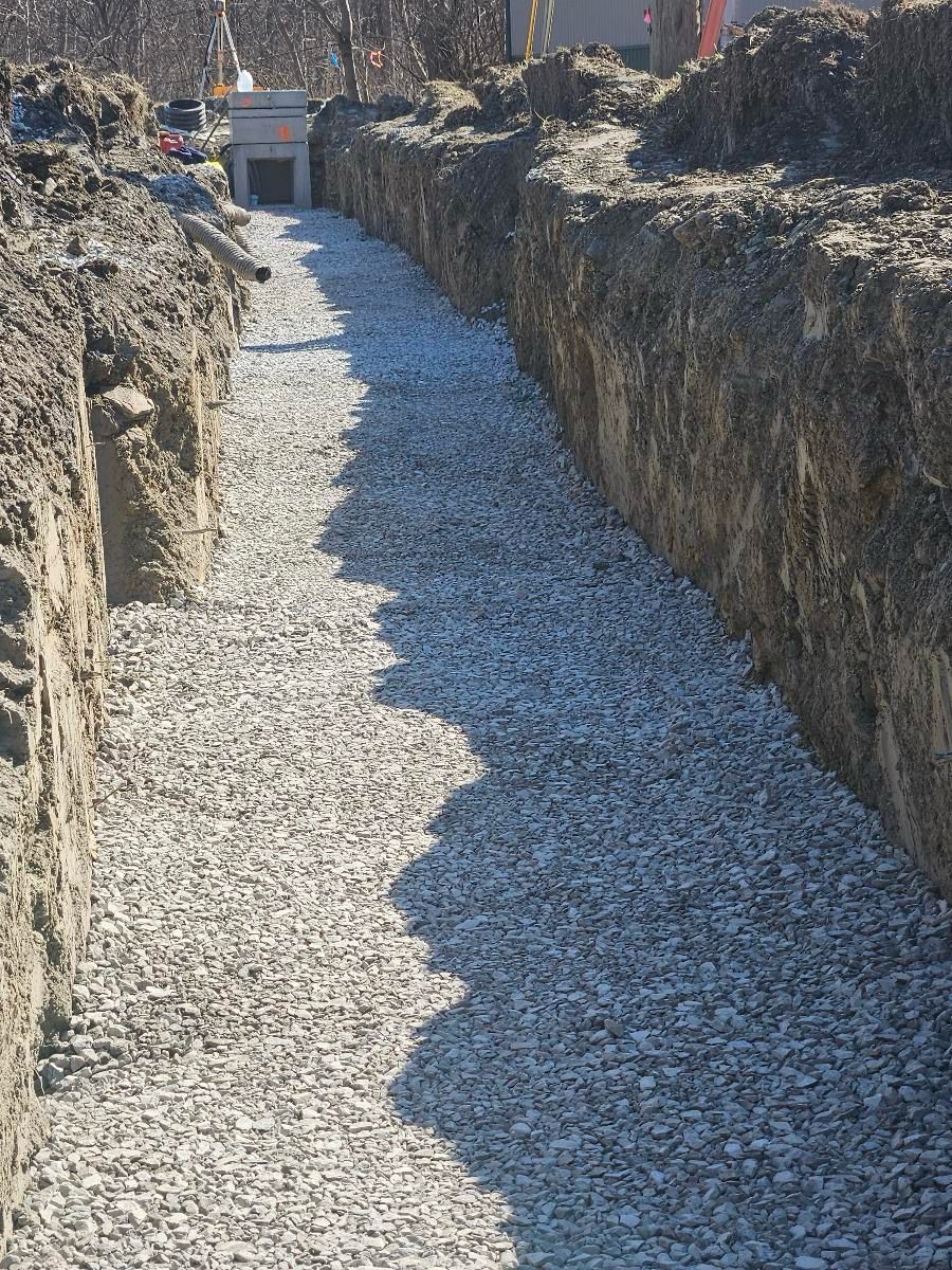 A gravel-filled construction trench stretches into the distance between two dirt walls.