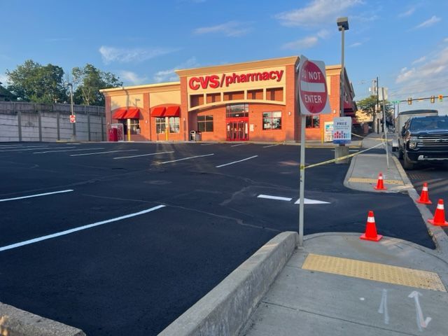A CVS Pharmacy with a freshly paved parking lot, marked by orange traffic cones and a 