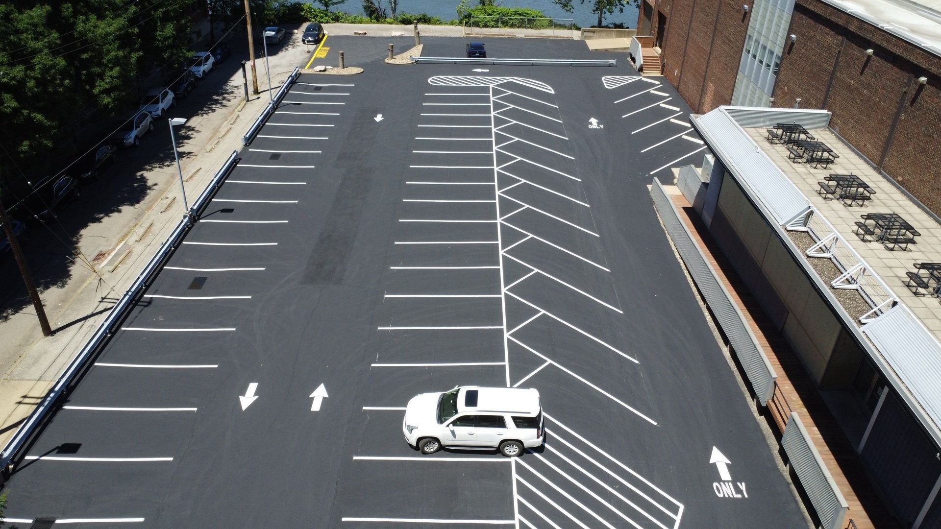 Aerial view of an empty parking lot with white lane markings and a single white van.