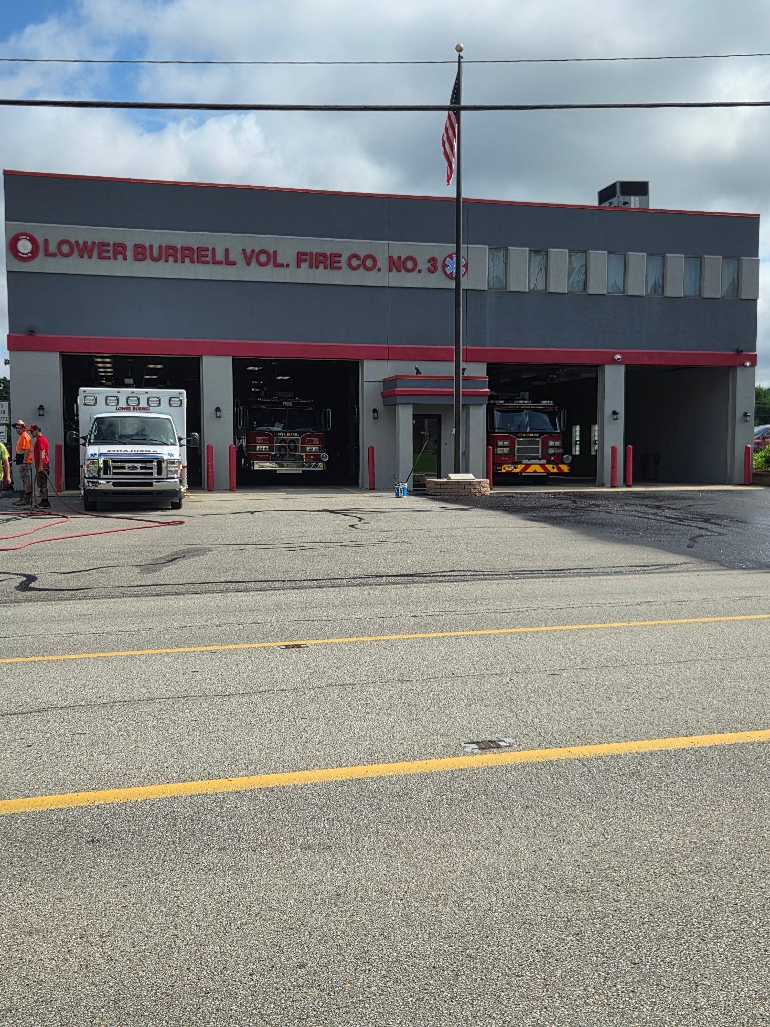 Fire station with two fire trucks parked in open bays under a red-and-white awning