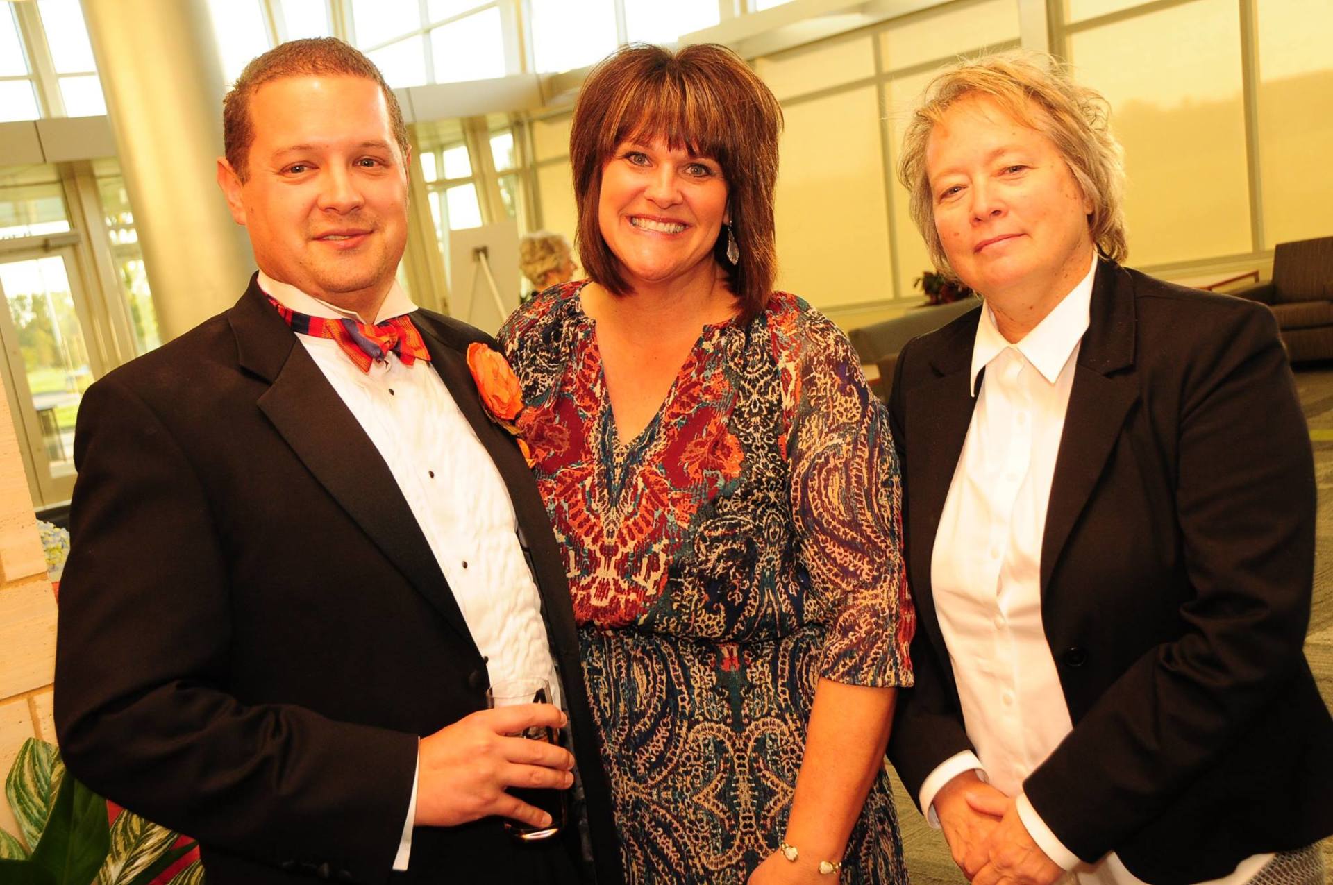 A man in a tuxedo is standing with two women