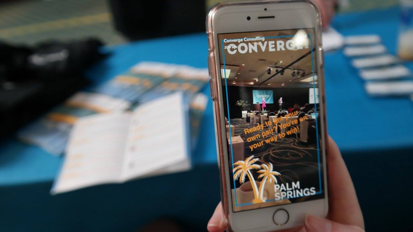 A person is holding a cell phone with a picture of palm springs on the screen.