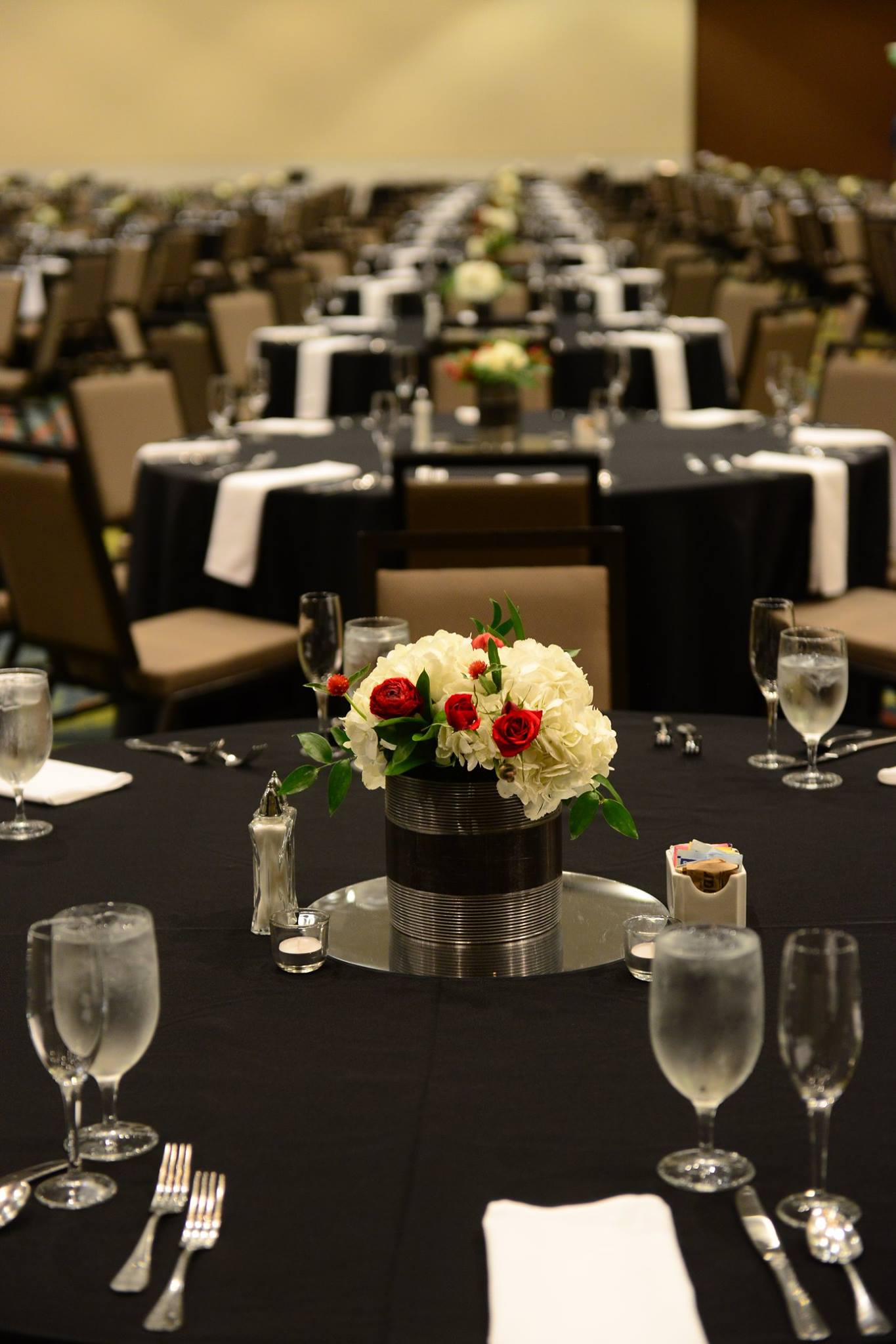 A table set for a wedding reception with a vase of flowers on it.