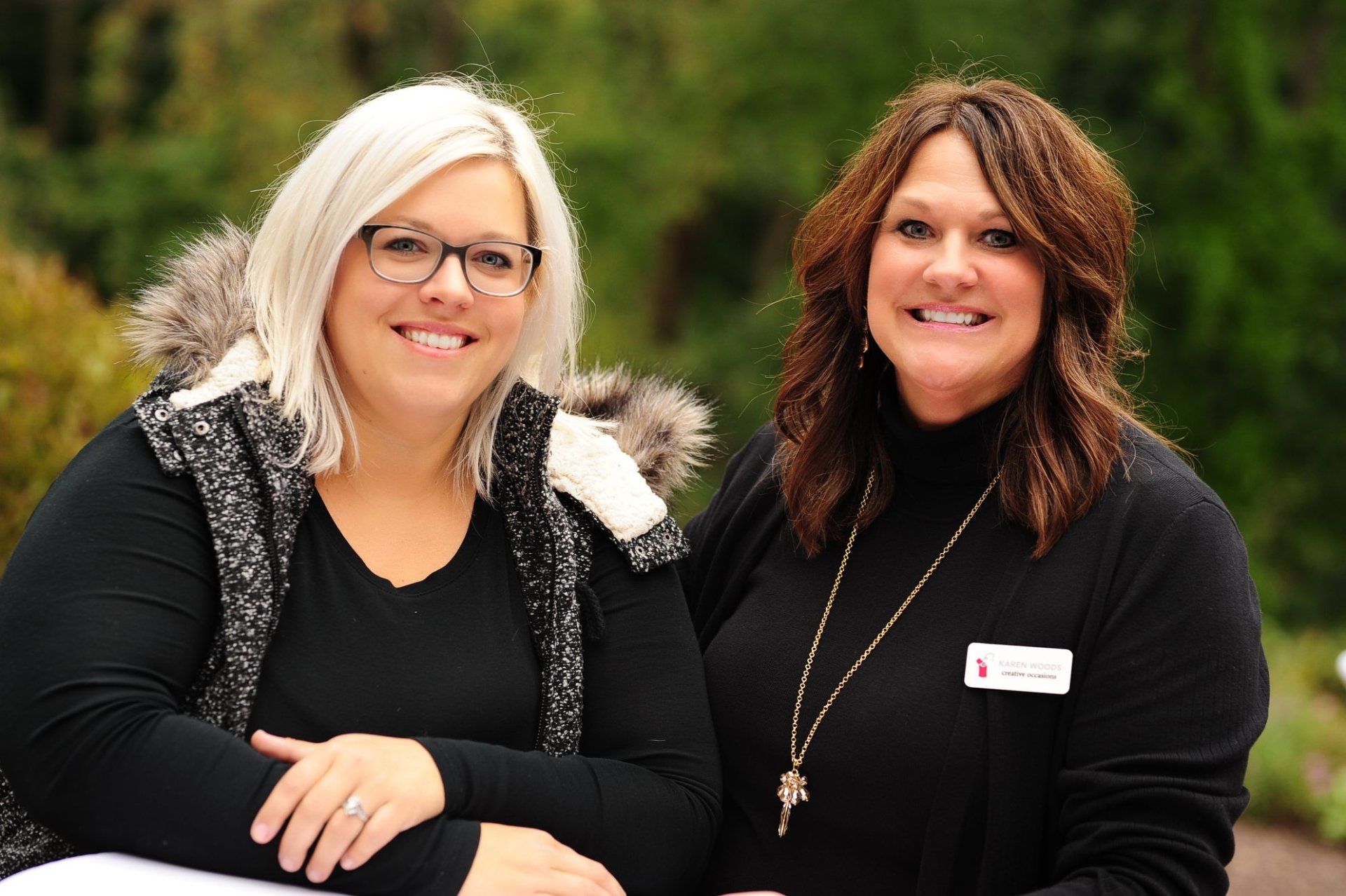Two women are standing next to each other and smiling for the camera.