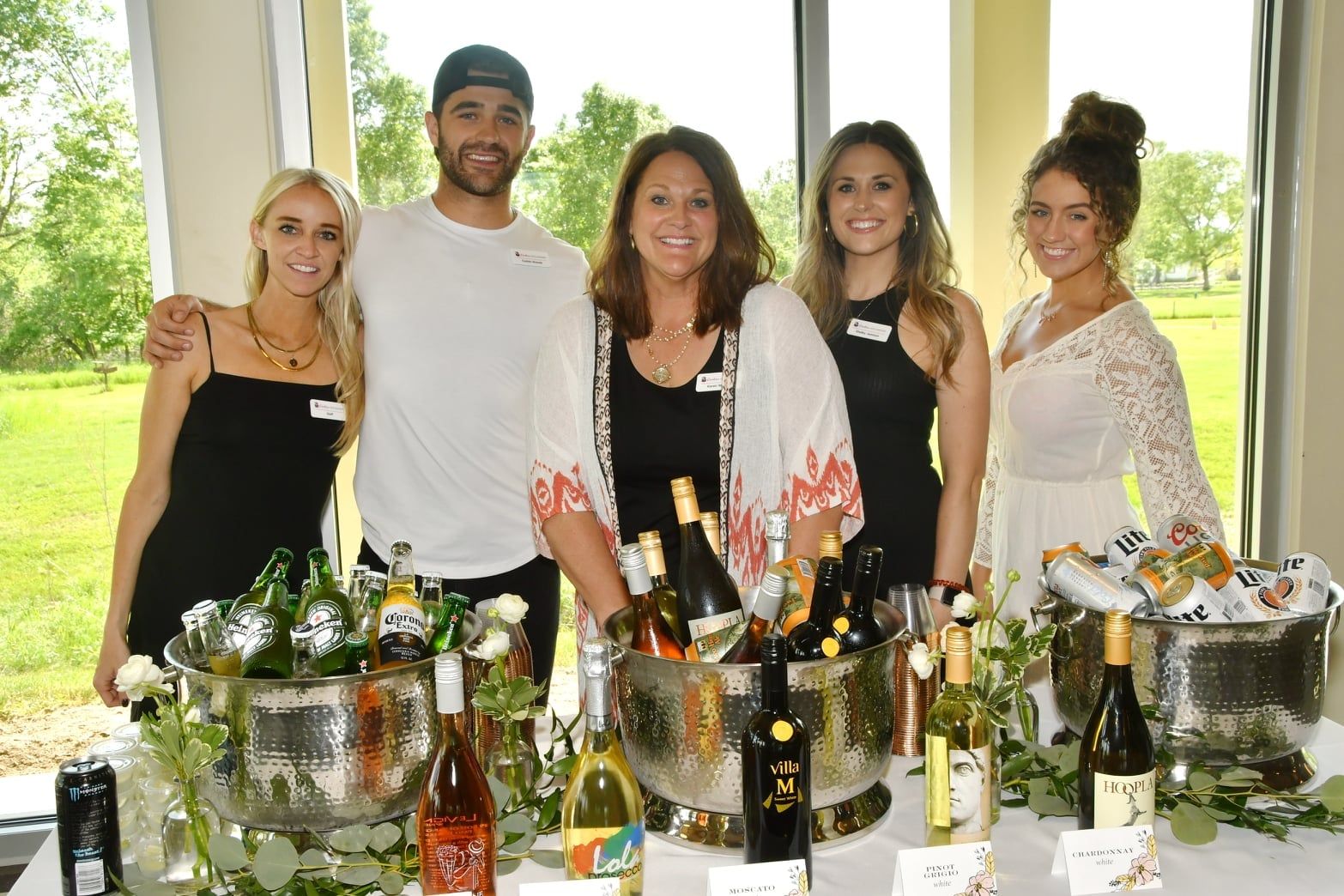 A group of people standing around a table with bottles of wine.