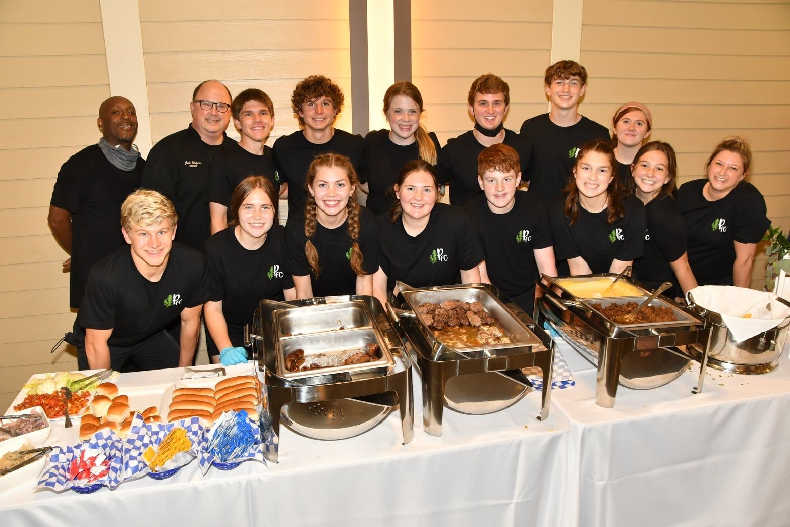 A group of people are posing for a picture in front of a buffet table.