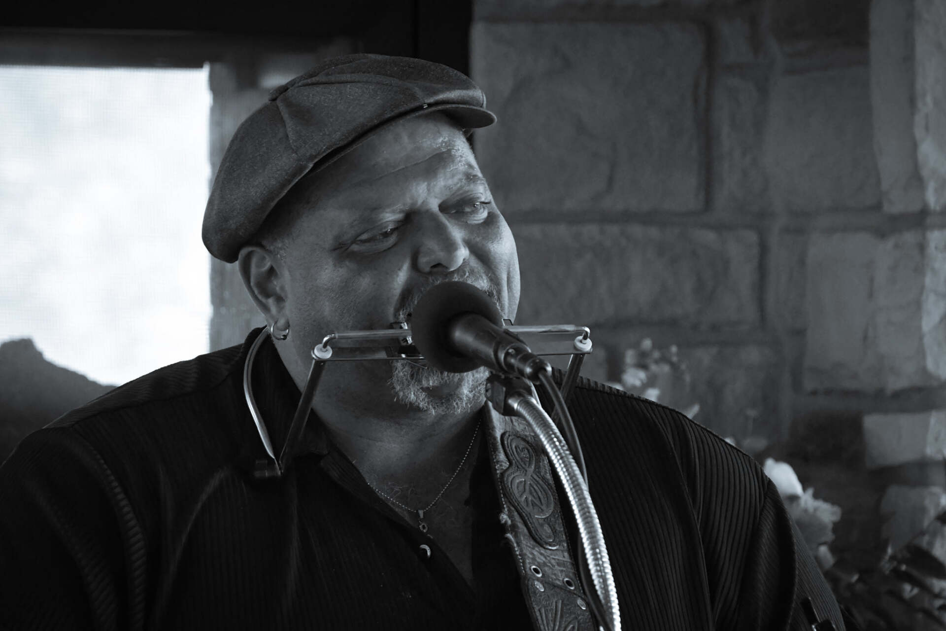 A man is playing a saxophone in front of a microphone in a black and white photo.