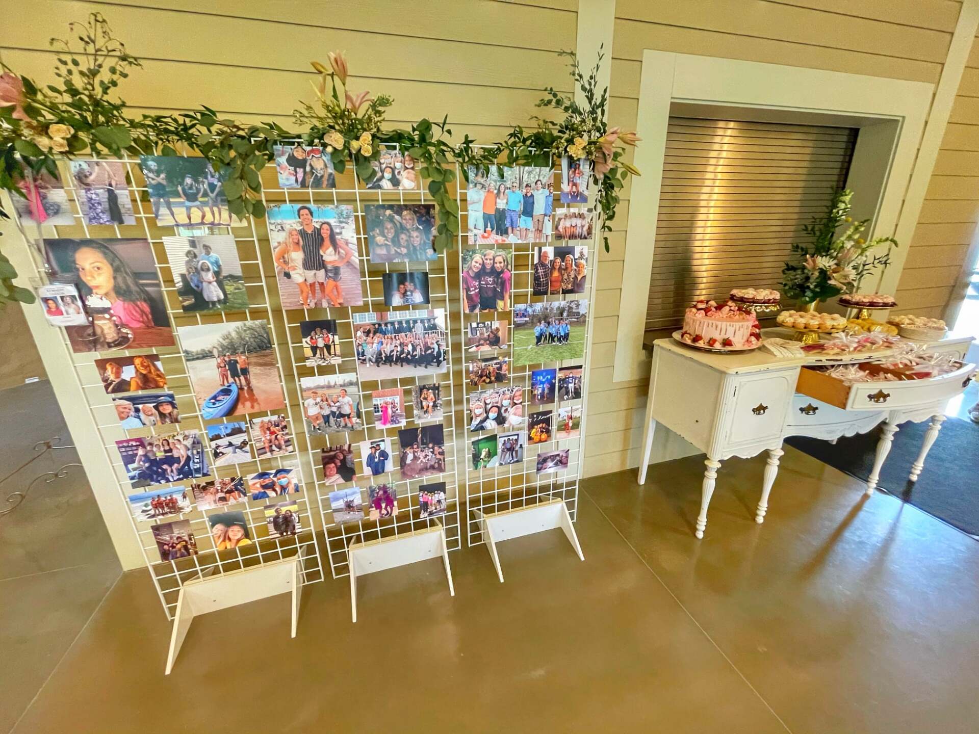 A wall with a lot of pictures on it and a table with cupcakes on it.