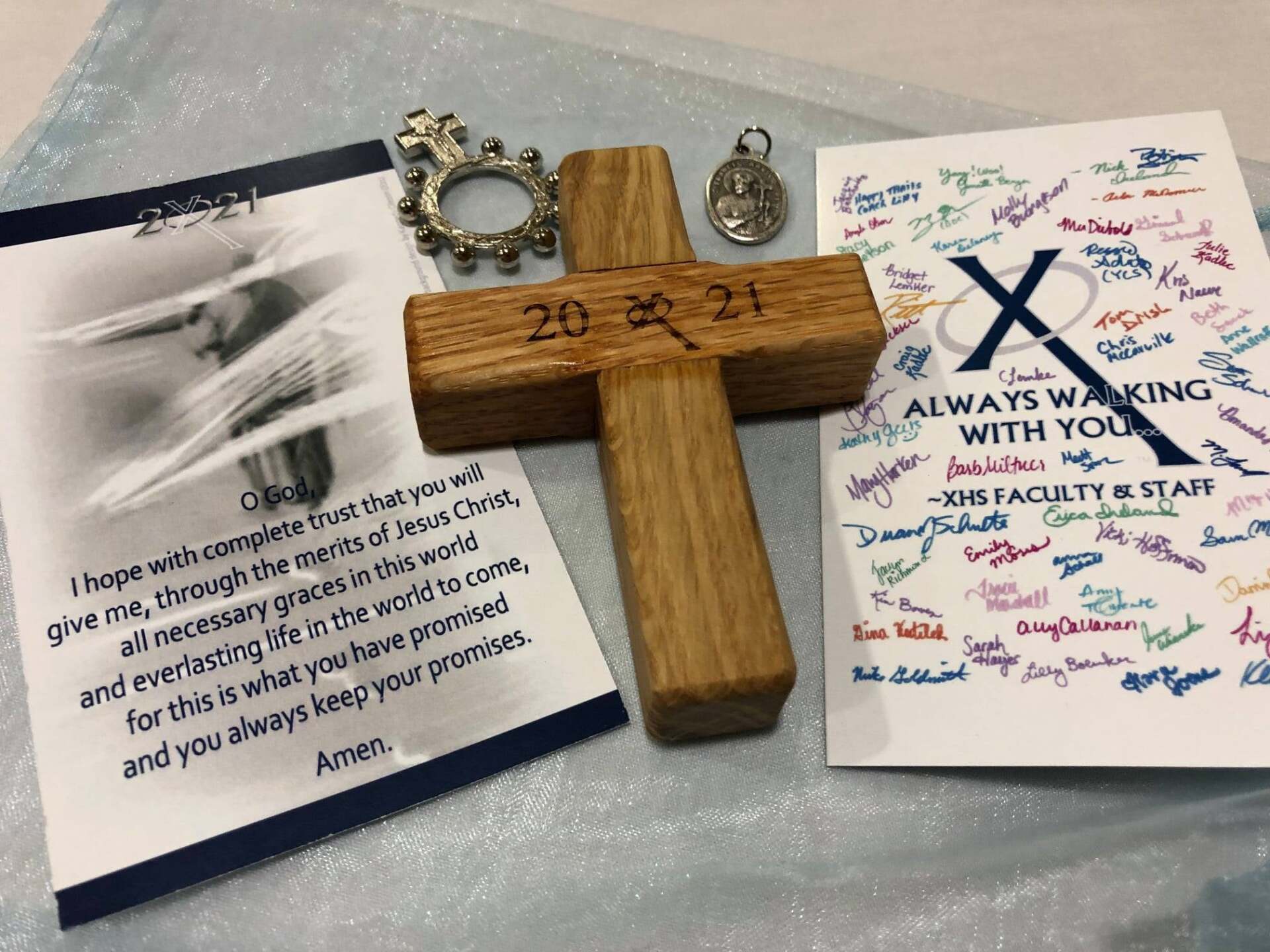 A wooden cross next to a card that says always walking with you