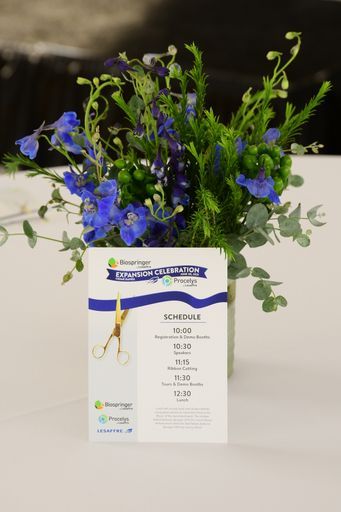 A vase filled with blue flowers and greenery is on a table.