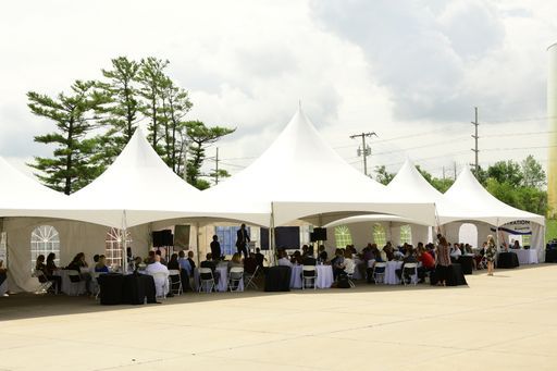 A group of people are sitting at tables under tents.