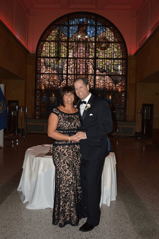 A man and woman standing in front of a stained glass window