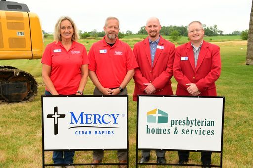 A group of people standing next to signs that say mercy and presbyterian homes and services.