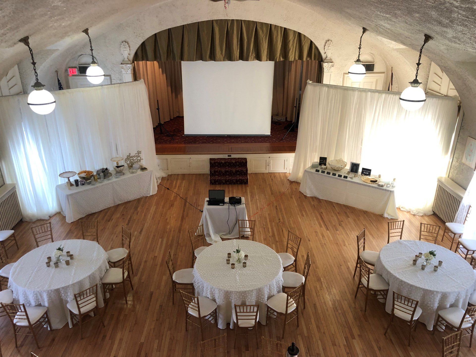 A large room with tables and chairs and a projector screen.