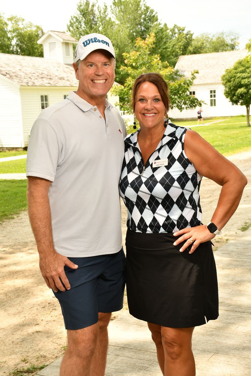 A man and a woman are standing next to each other on a dirt road.