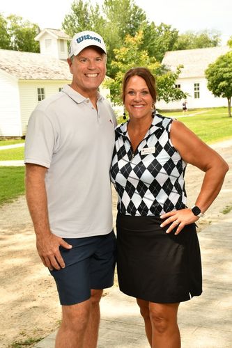 A man and a woman are standing next to each other on a dirt road.