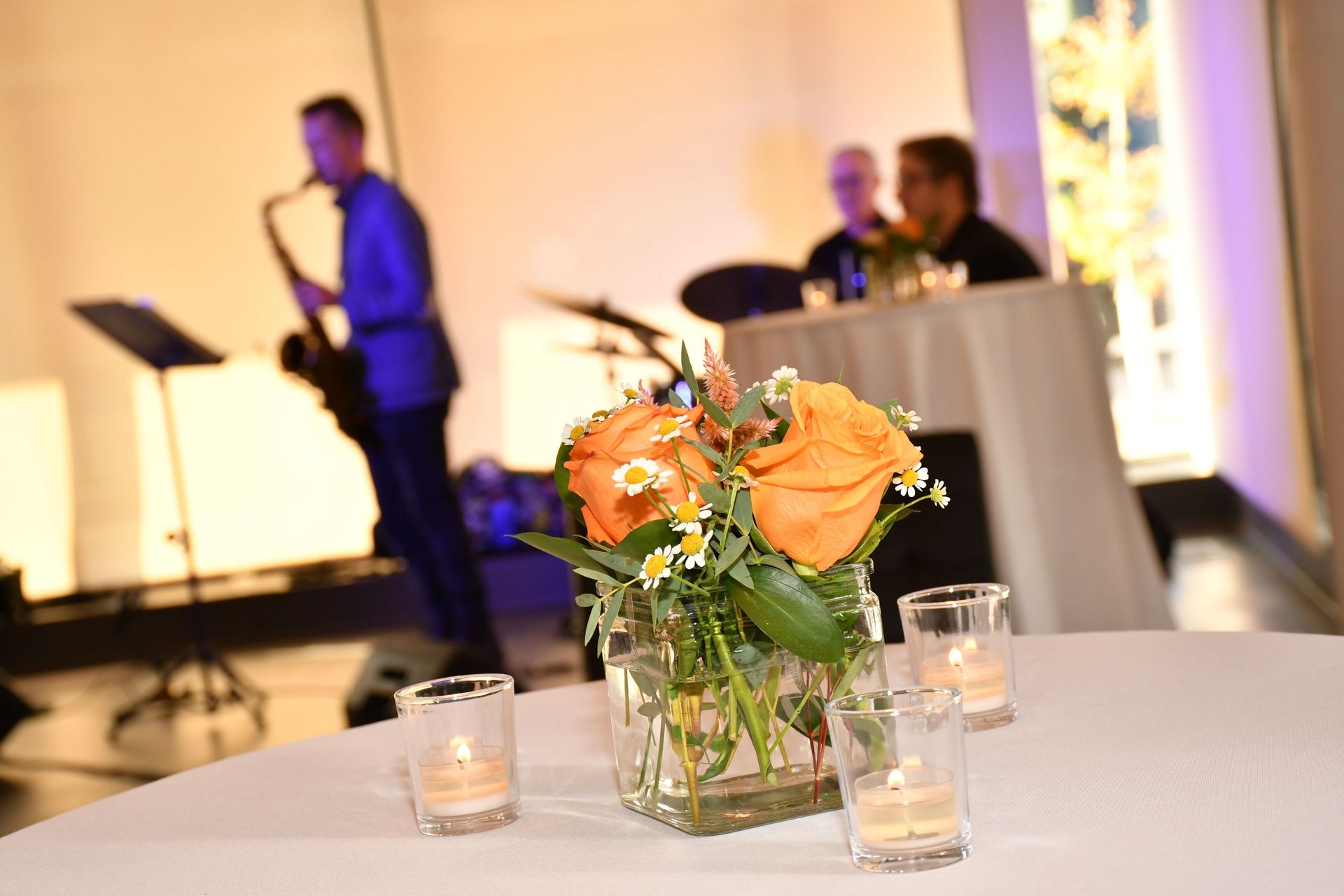 flowers and candles on the table with musicians in the background