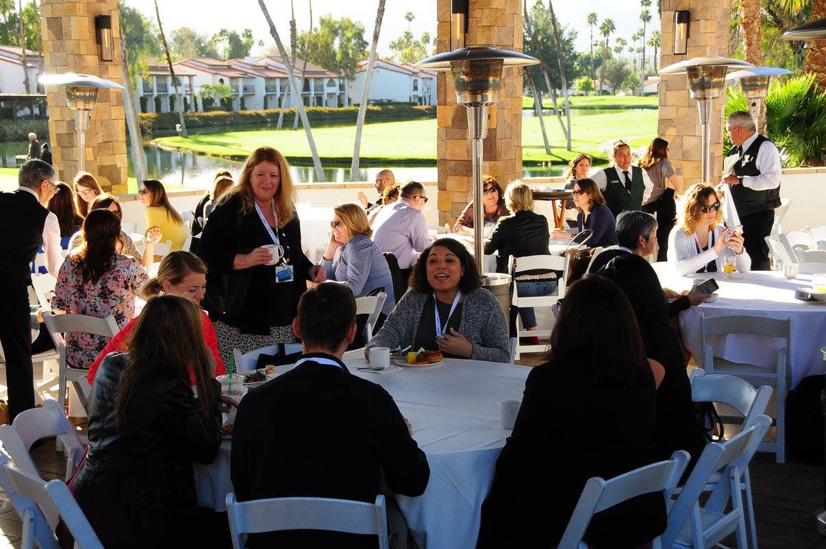 A group of people are sitting at tables outside.