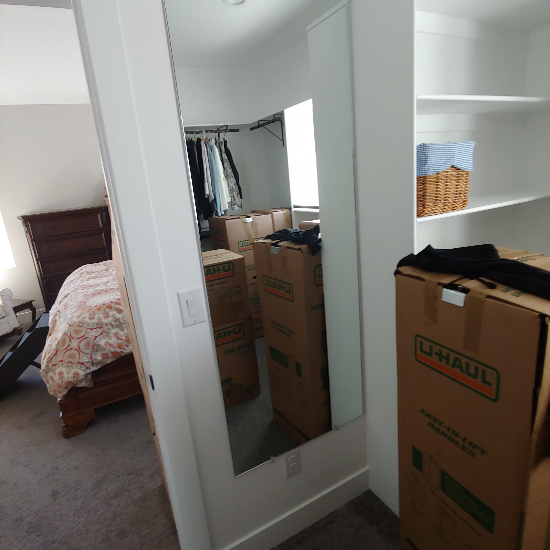 A u-haul box sits next to a mirror in a bedroom