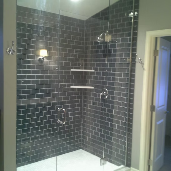 A shower stall with a brick wall and a glass door