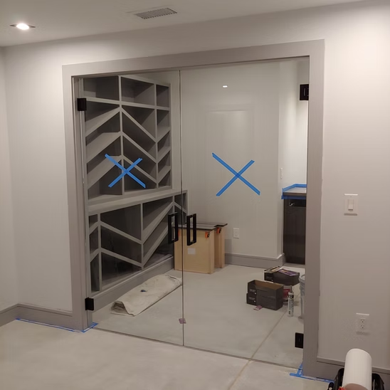 A room with a glass door and a blue x on the wall