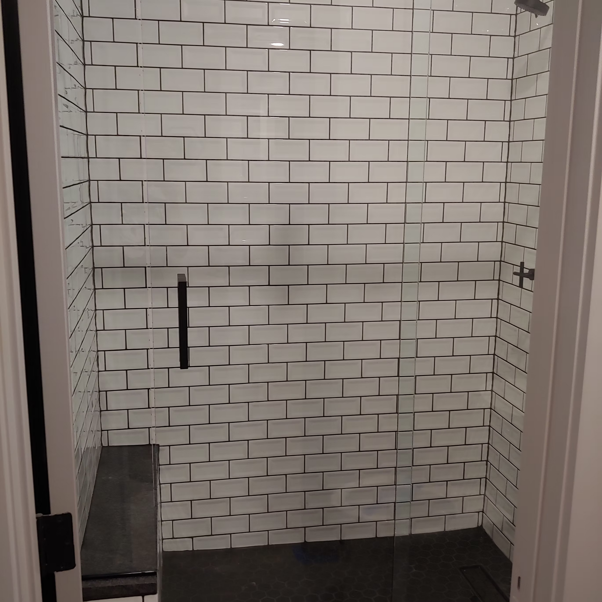A shower with white tiles and a glass door
