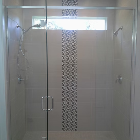 A bathroom with a sliding glass shower door and a window.