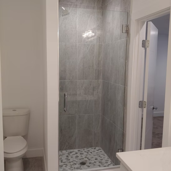 A bathroom with a toilet and a walk in shower.