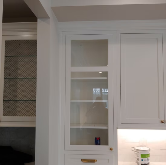 A kitchen with white cabinets and glass doors