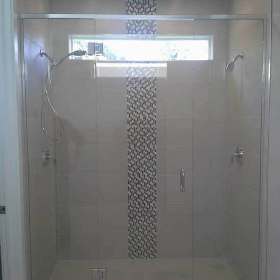 A shower with a sliding glass door and a window.