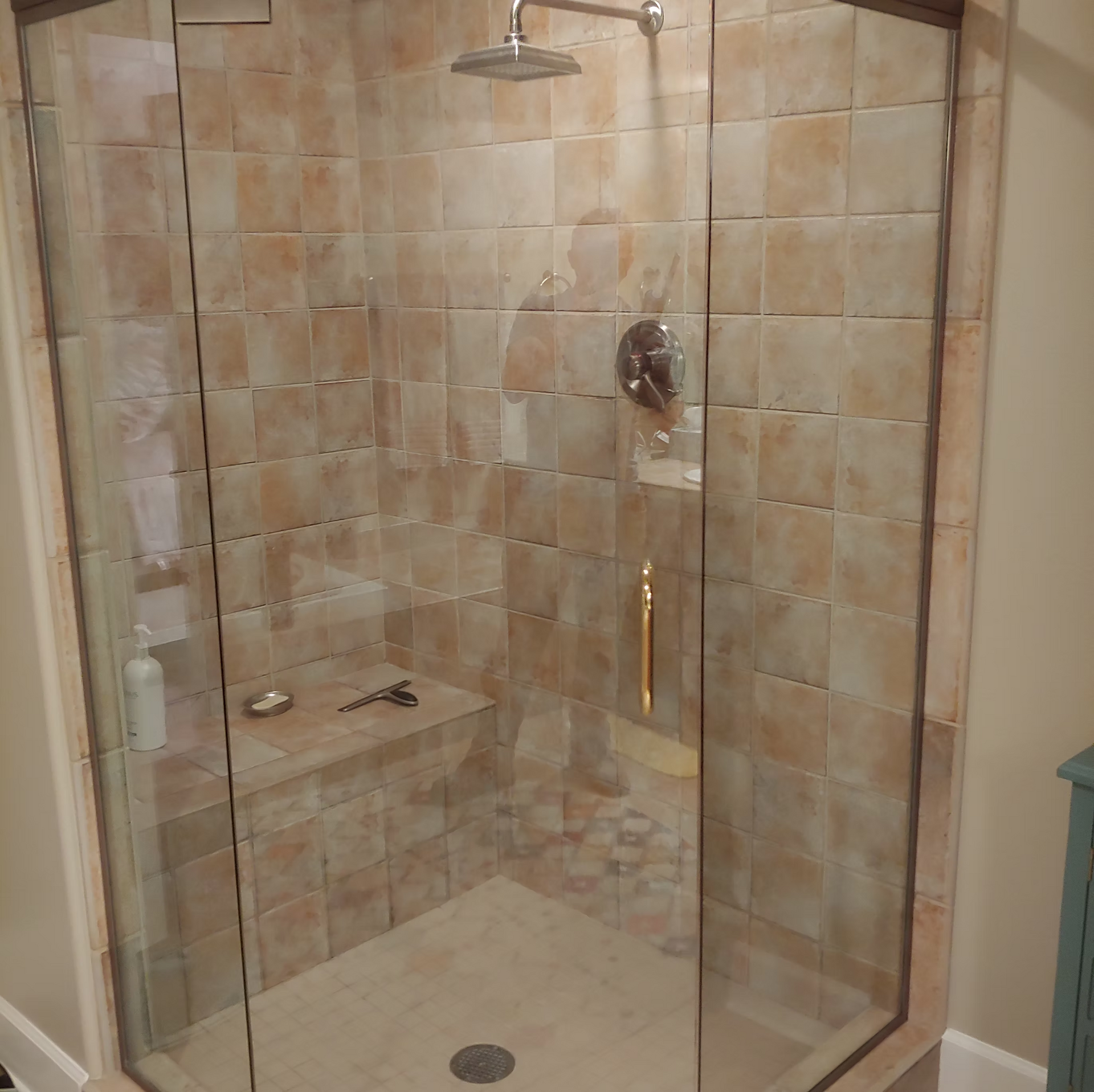 A shower with a glass door and a shower head