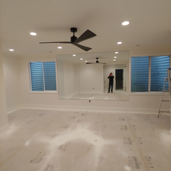 A room with a large mirror and a ceiling fan