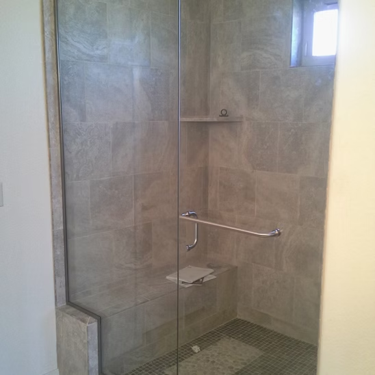 A bathroom with a walk in shower with a glass door.