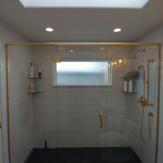 A bathroom with a glass shower door and a window