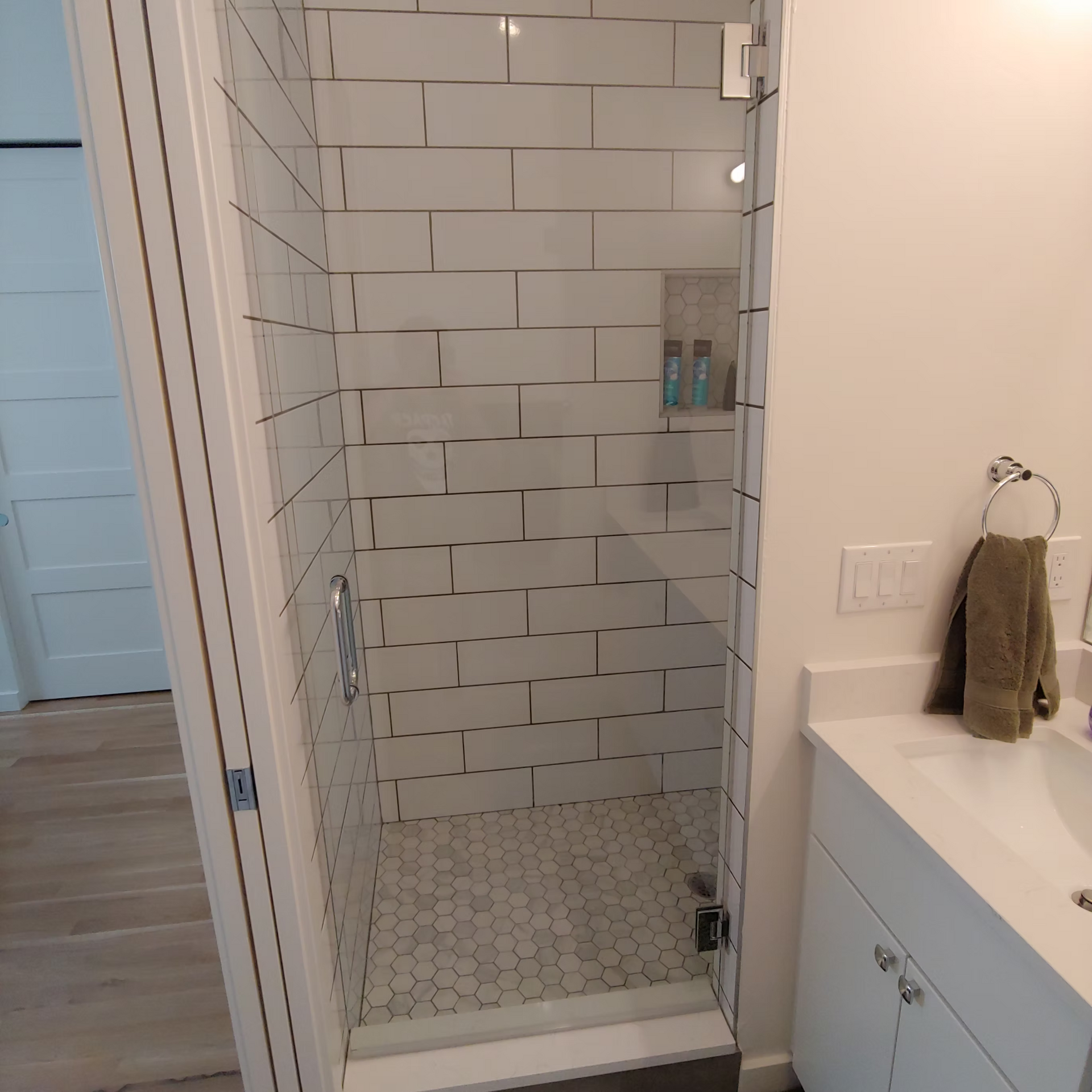 A bathroom with a walk in shower and a sink