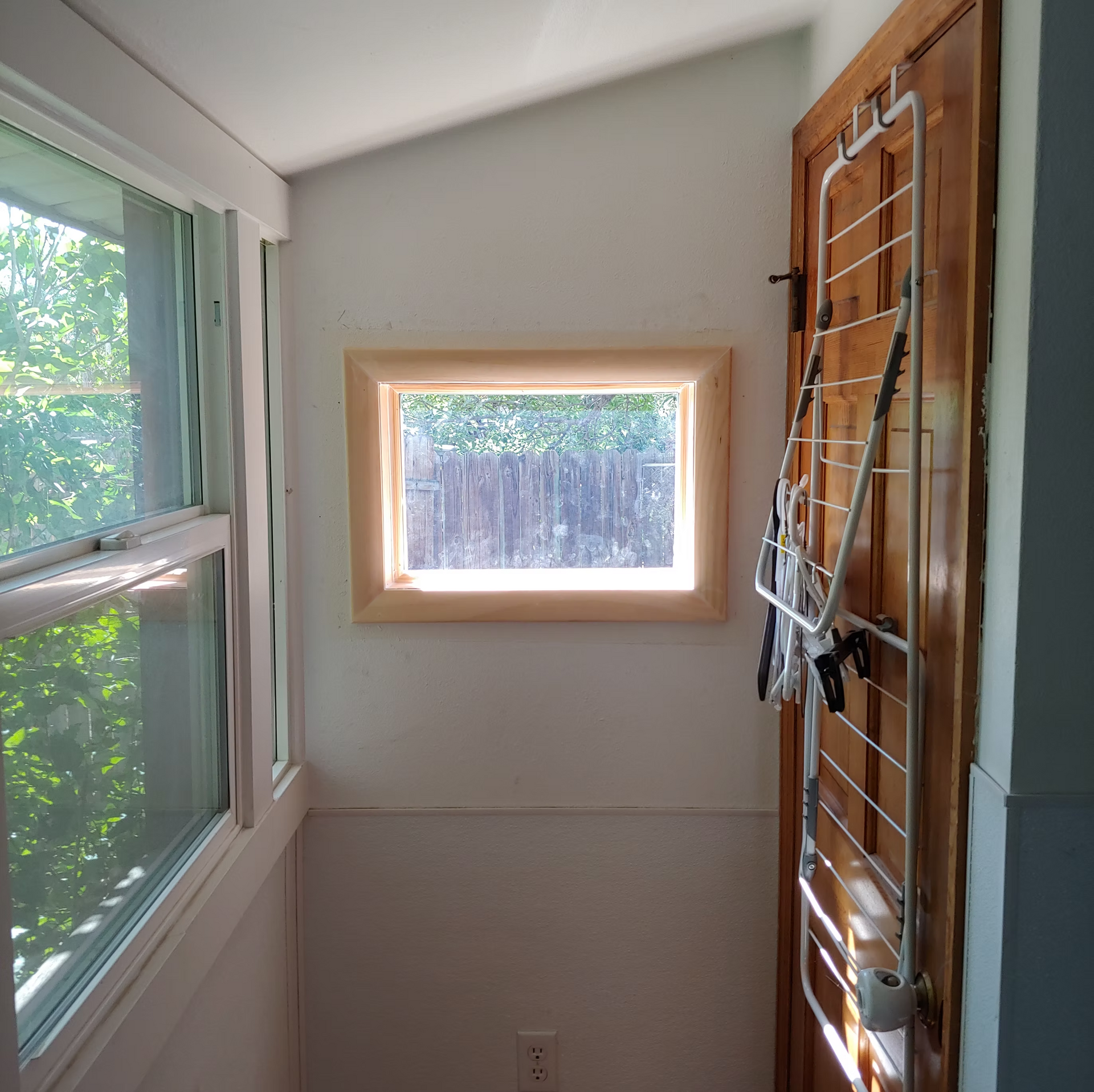 A room with a window and a clothes drying rack
