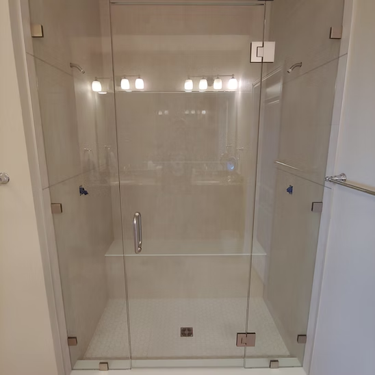 A bathroom with a walk in shower with a glass door.