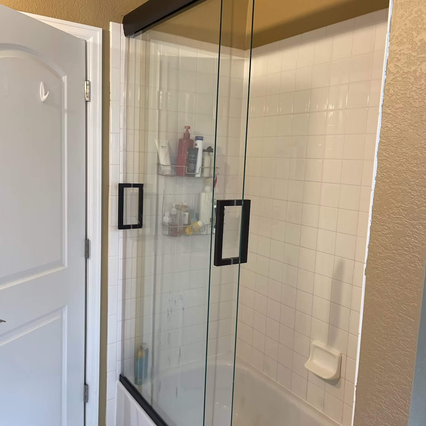 A bathroom with a glass shower door and a bathtub.