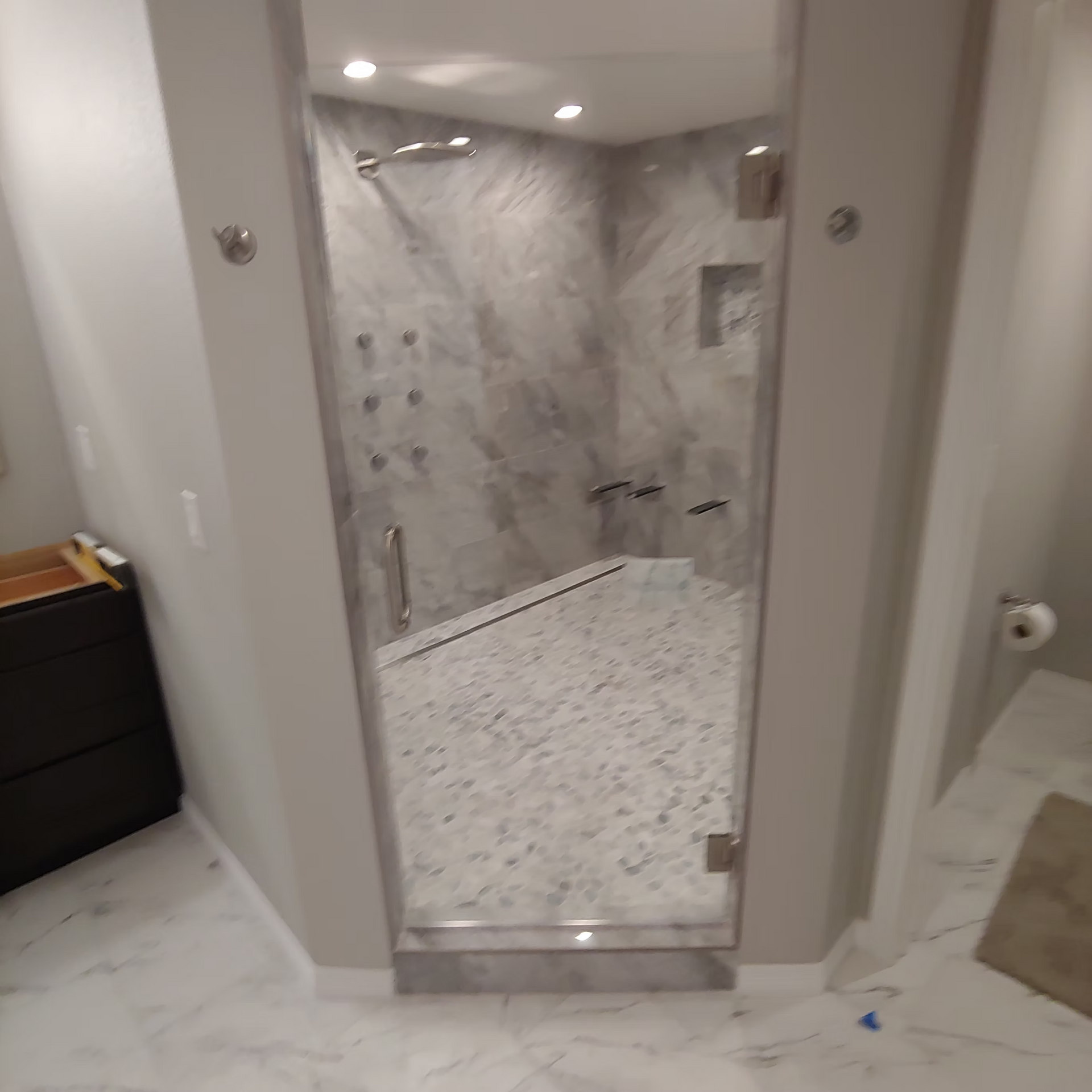 A bathroom with a walk in shower and a glass door.