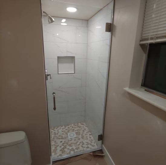 A bathroom with a toilet and a shower with a glass door.