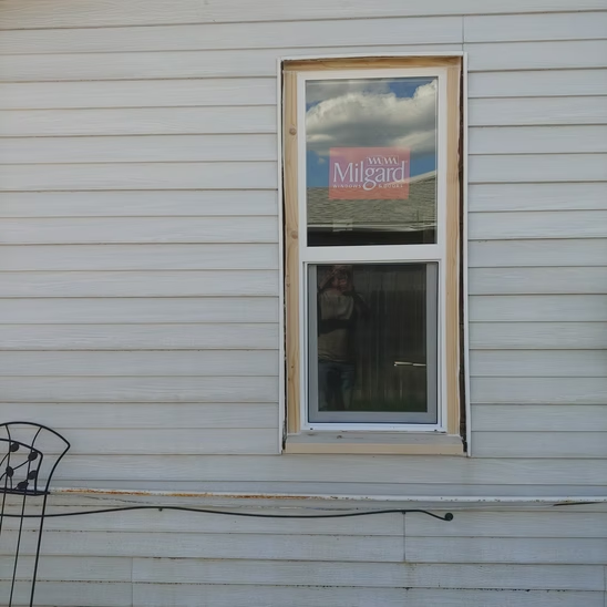 A window on the side of a house has a sign on it that says 