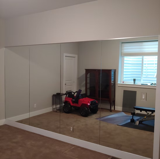 A red toy car is parked in a room with a large mirror.